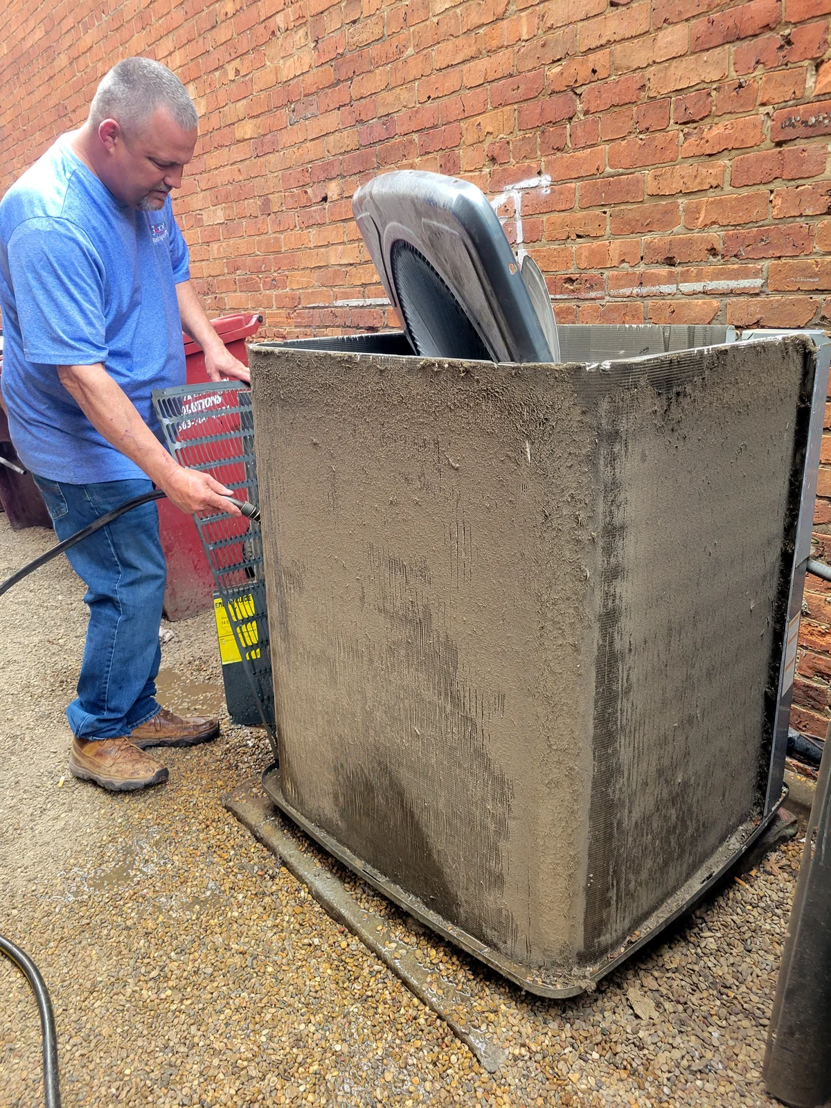Technician cleaning dirty AC condenser coil